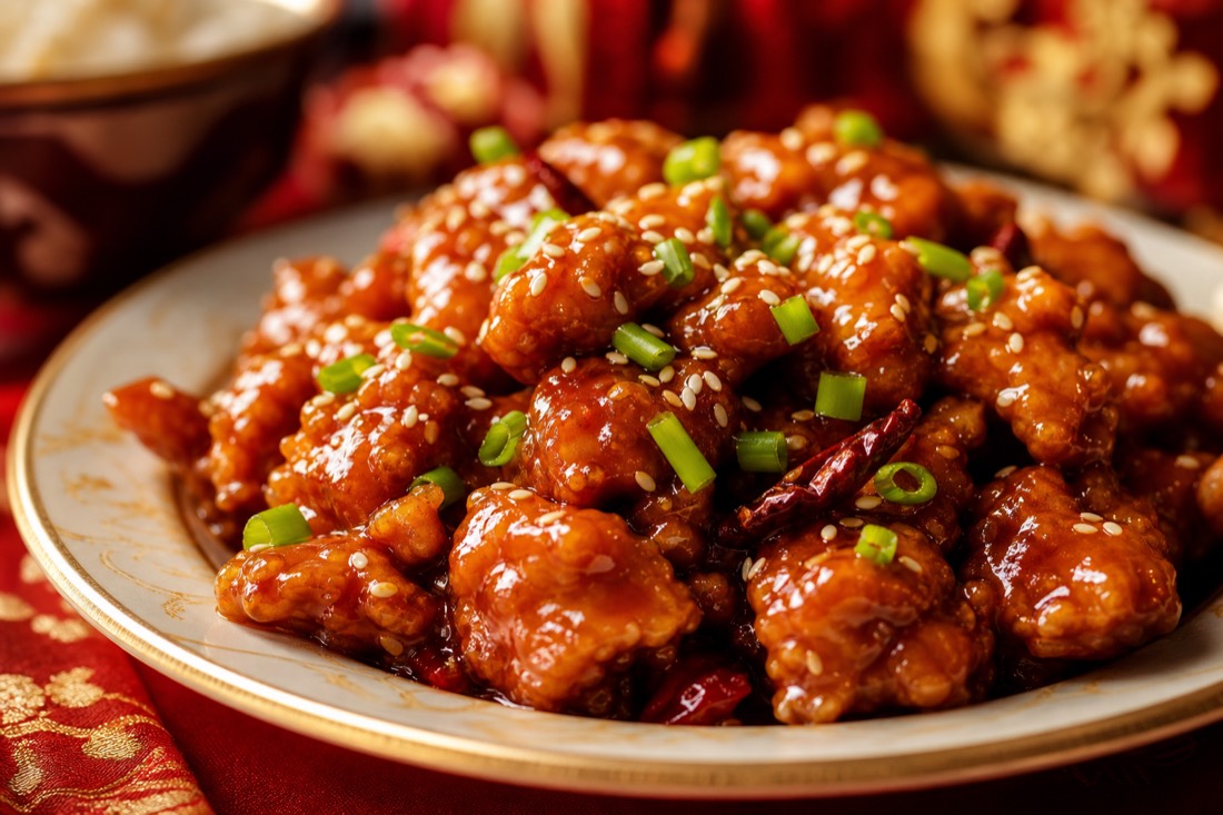A glossy plate of sesame chicken with scallions